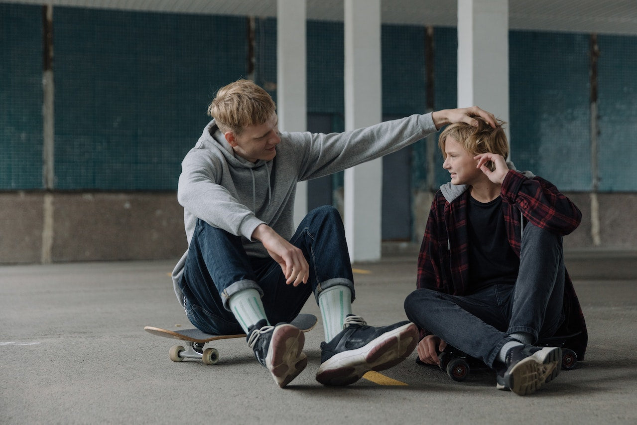 brothers sitting on skateboard talking